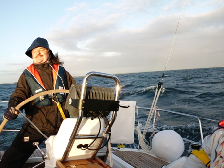 Robbie mit Rettungsweste am Ruder einer Segelyacht auf stümischem Meer